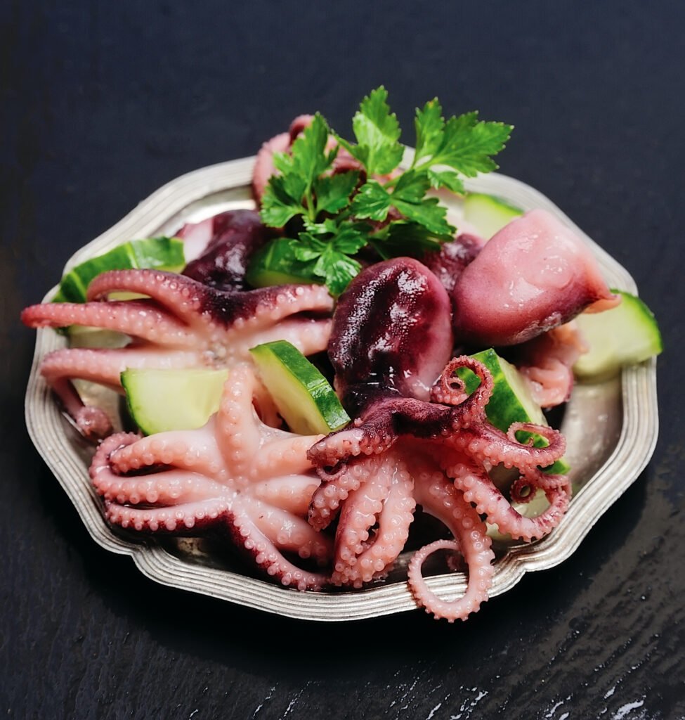 Ensalada de pulpo con calabacín y perejil en un plato blanco