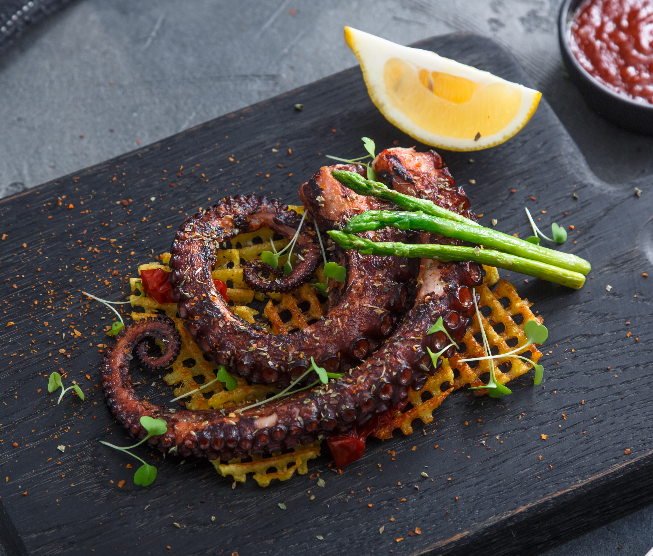 Tentáculo de pulpo a la brasa emplatado con espárragos verdes